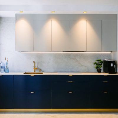 Cocina moderna a medida en azul con encimera efecto mármol y grifería dorada